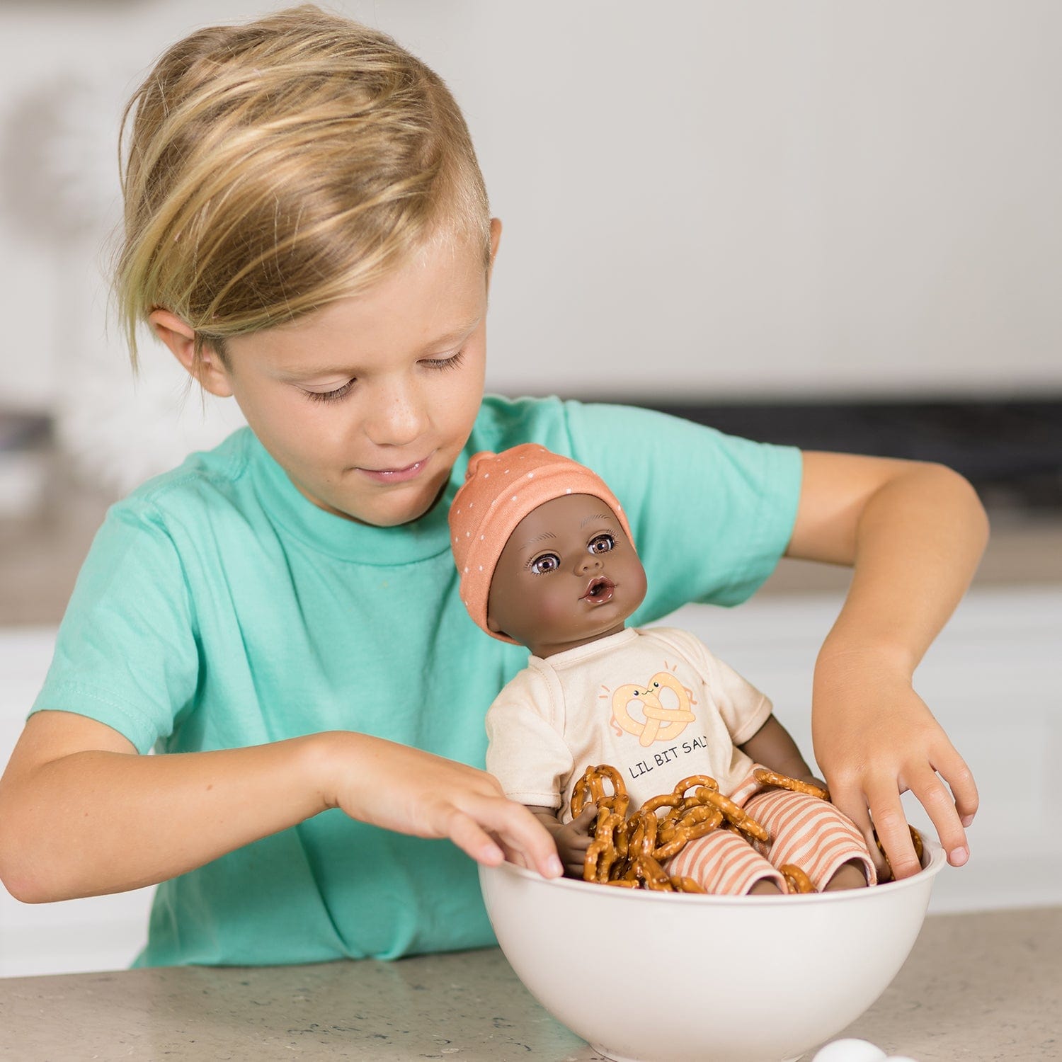 Adora Sweet Pretzel baby doll set includes one 13-inch African American doll, pretzel-printed shirt, pants, matching beanie, blue baby bottle.  Made for Ages 1+.